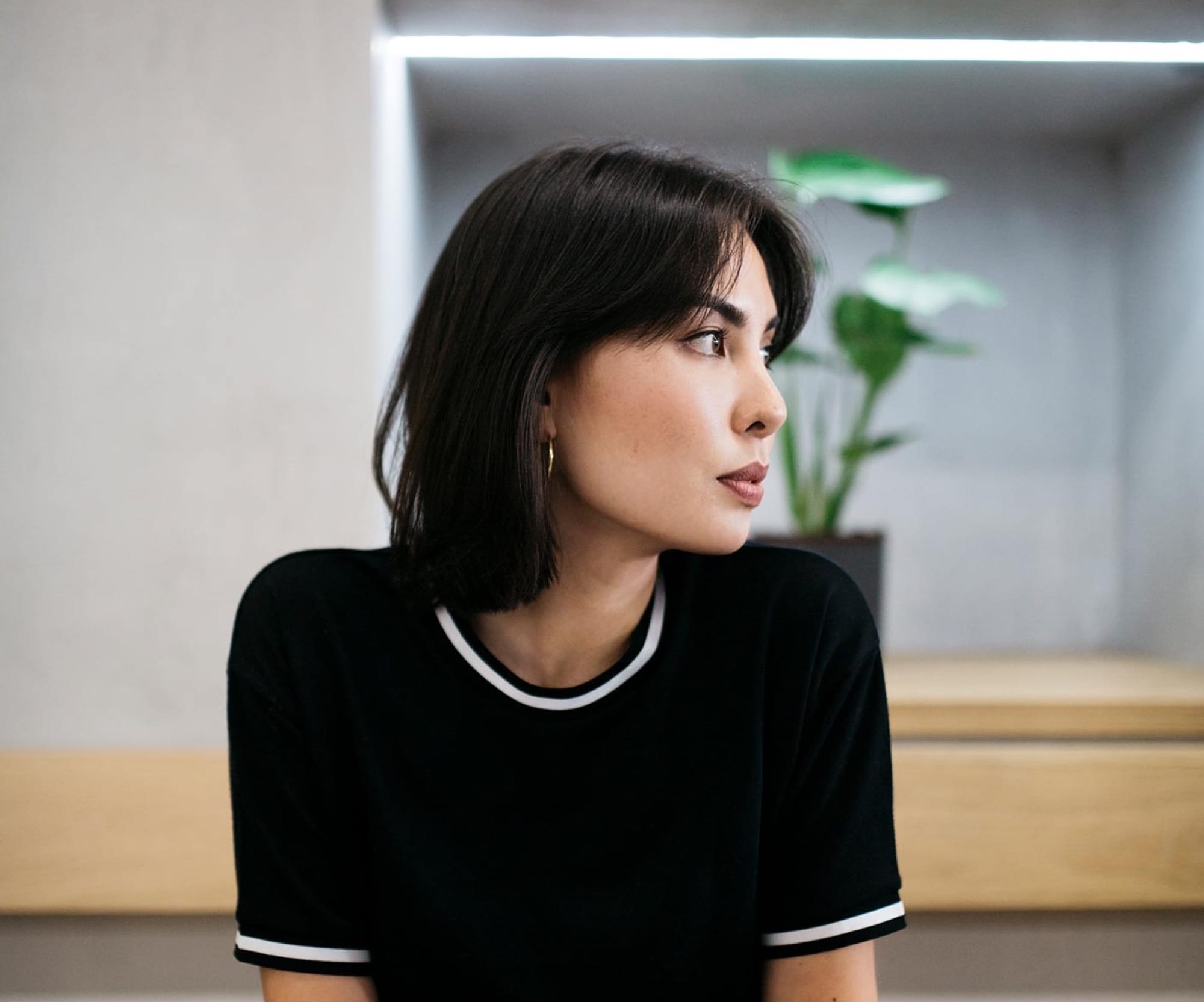 A founder in a black top looking away thoughtfully in a bright studio