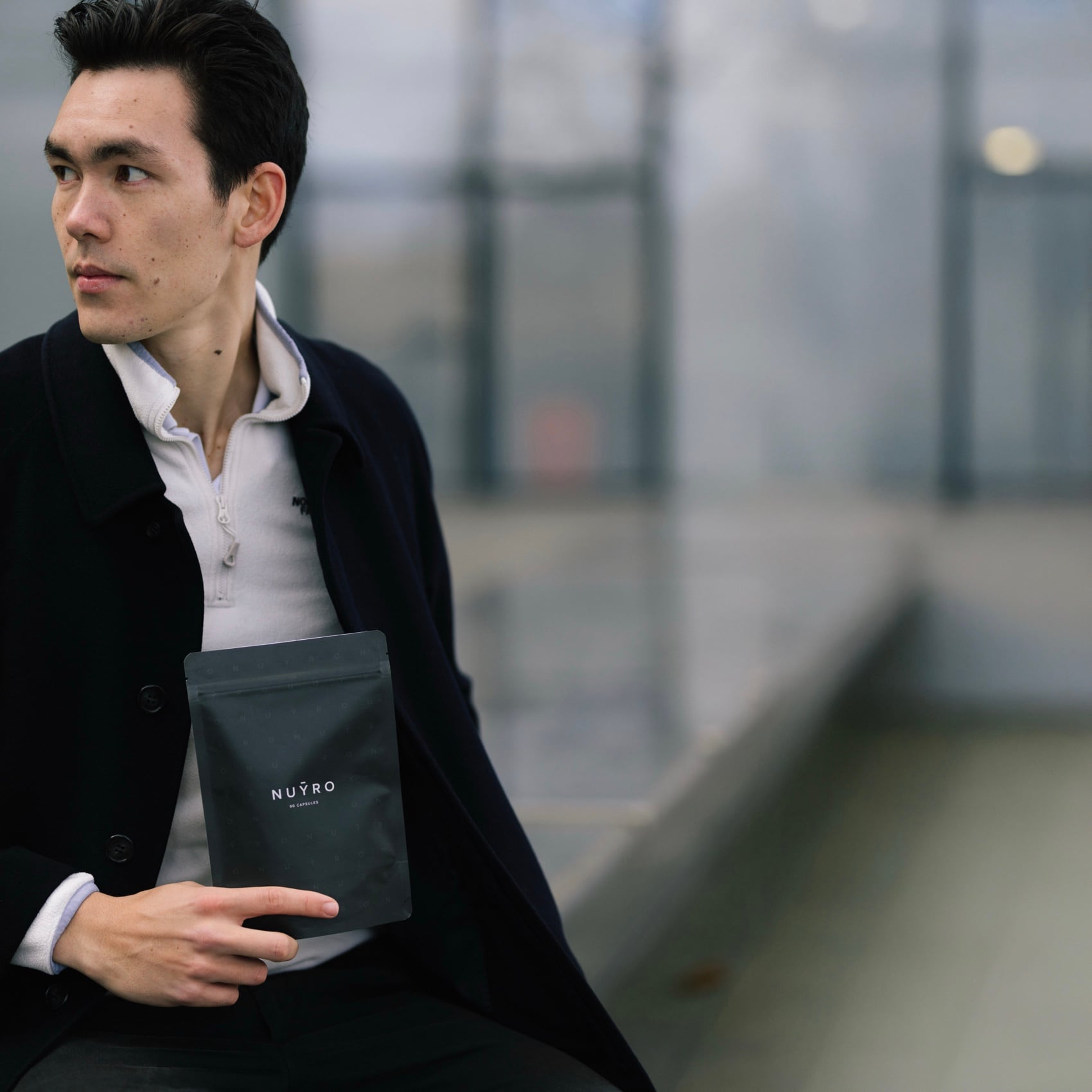 A founder holding a dark NUYRO capsule pouch